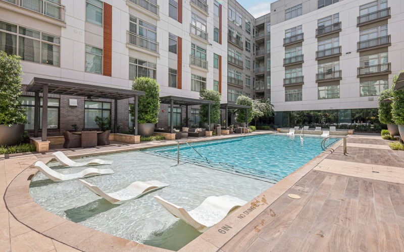 resort inspired pool area with sundeck chairs and cabanas